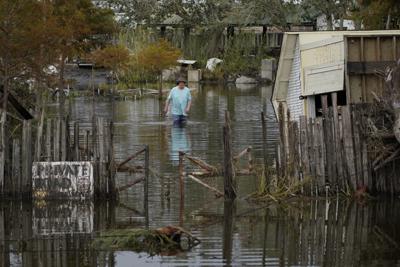 Un hombre camina por una calle inundada tras el paso del huracán Ida, el miércoles 1 de septiembre de 2021 en Lafitte, Luisiana.  (AP Foto/John Locher)