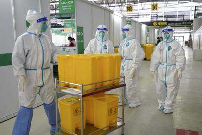 En esta fotografía difundida por la Agencia de Noticias Xinhua de China, muesetra a trabajadores médicos con trajes protectores que se desplazan por el Nuevo Centro Internacional de Exposiciones de Shanghai, convertido en una instalación de cuarentena para personas con síntomas leves de COVID-19 o asintomáticas en Shanghai, el viernes 1 de abril de 2022. (Xinhua vía AP)