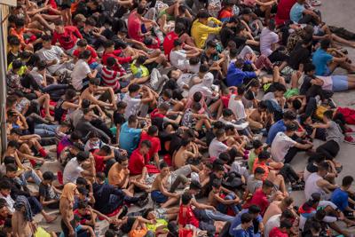 Menores migrantes en un almacén utilizado como refugio esperan a realizarse la prueba de COVID-19 en Ceuta, España, cerca de la frontera con Marruecos, el 19 de mayo de 2021. (AP Foto/Bernat Armangue, File)