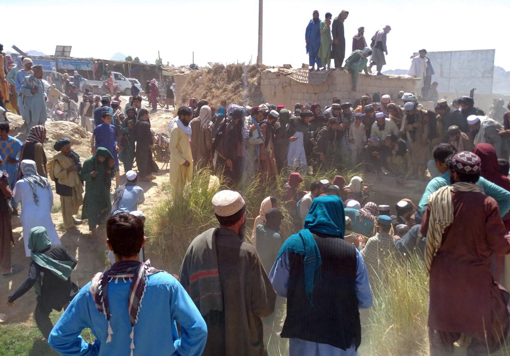 Taliban fighters and Afghans gather around the body of a member of the security forces who was killed, inside the city of Farah, capital of Farah province, southwest Afghanistan, Wednesday, Aug. 11, 2021. Afghan officials say three more provincial capitals have fallen to the Taliban, putting nine out of the country’s 34 in the insurgents’ hands amid the U.S. withdrawal. The officials told The Associated Press on Wednesday that the capitals of Badakhshan, Baghlan and Farah provinces all fell. (AP Photo/Mohammad Asif Khan)