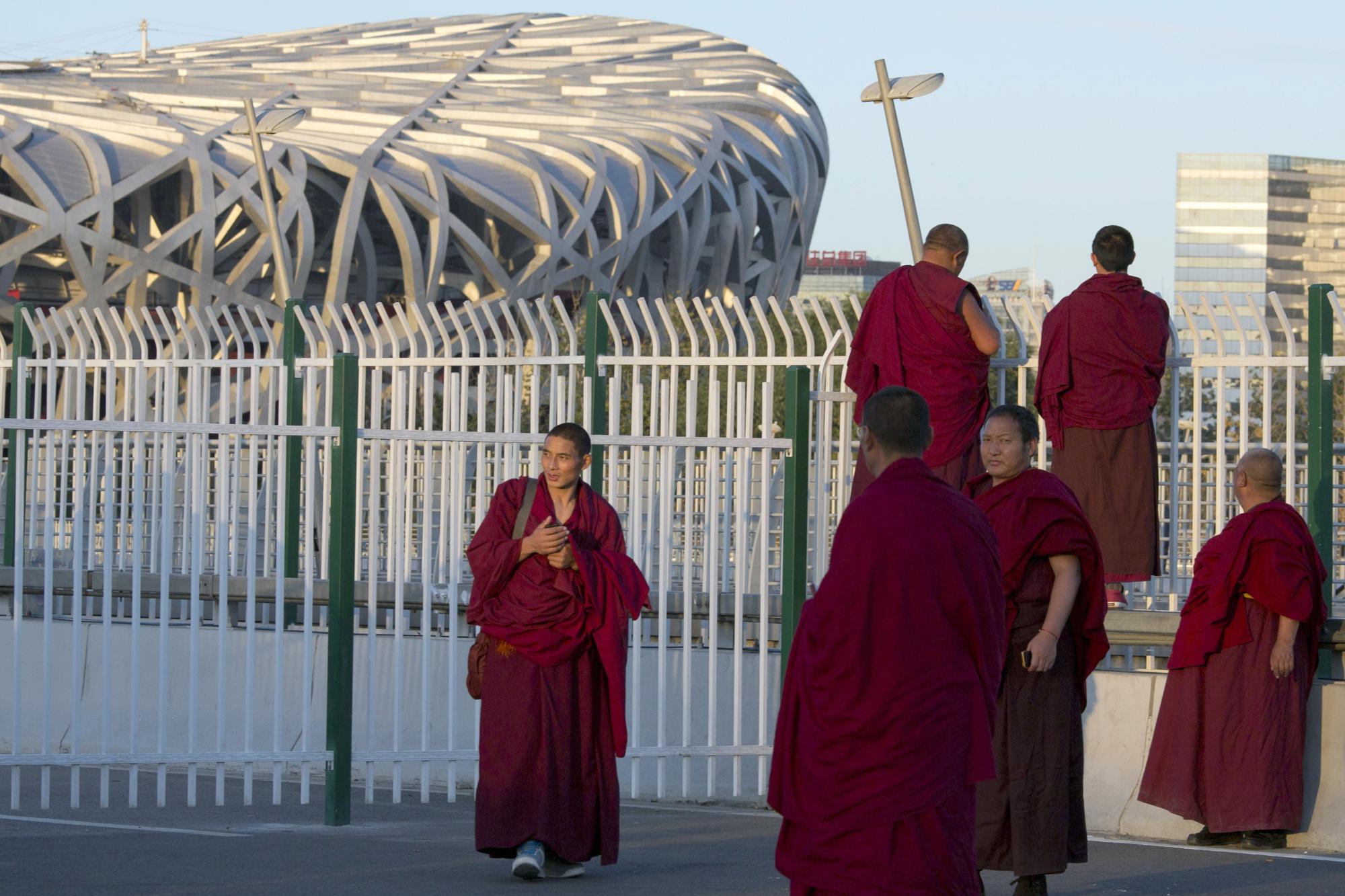 FILE - Tibetan lamas visit the Olympic green area near the iconic Bird's Nest National Stadium which held the opening ceremonies of the Summer and Winter Olympics in Beijing on Nov. 6, 2014. Ahead of the Beijing summer Olympics 14 years ago, deadly demonstrations erupted across the Tibetan plateau. But now Tibet has fallen silent, even as the Olympic games come to Beijing again. (AP Photo/Ng Han Guan, File)
