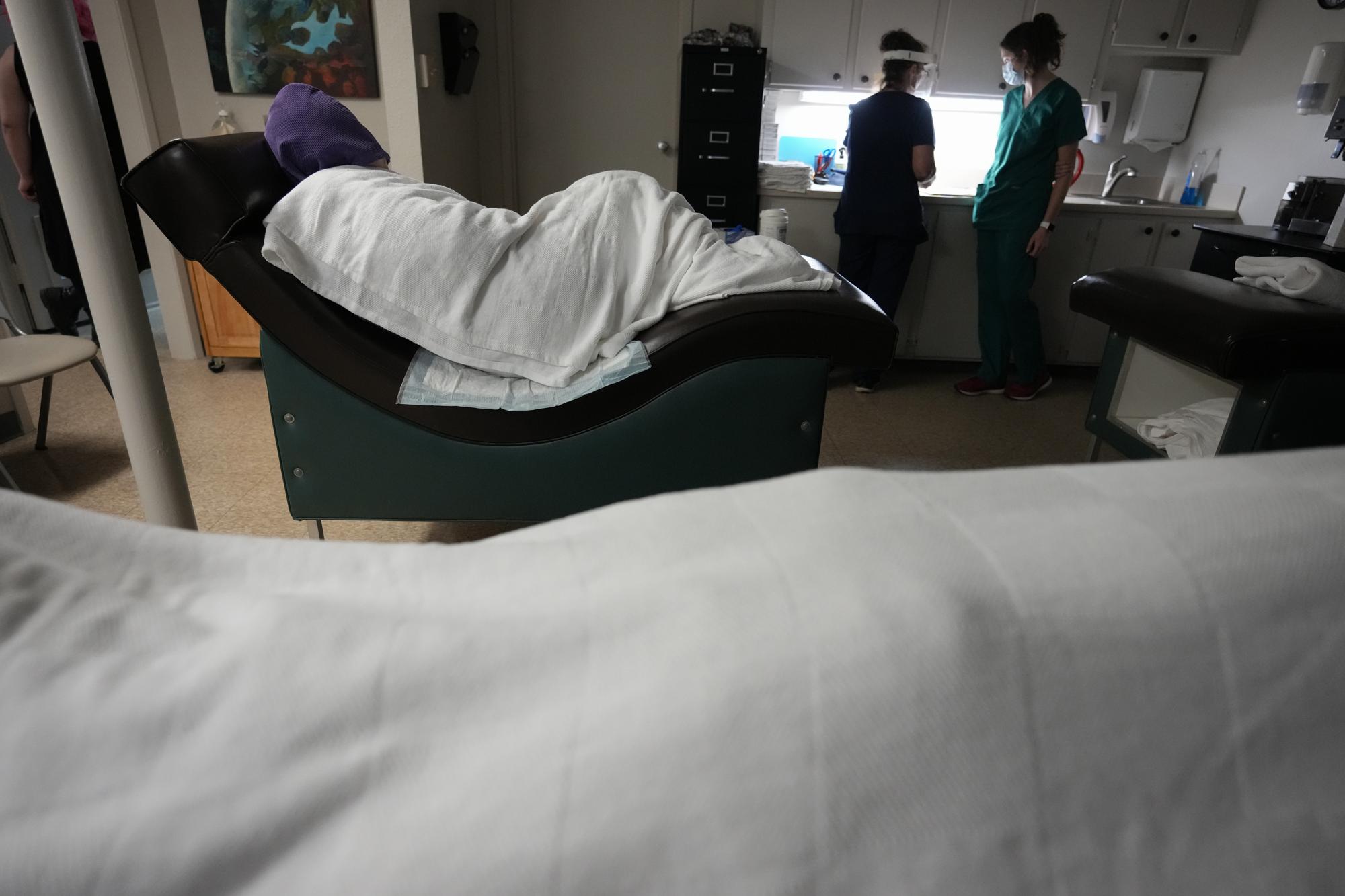 A woman naps, bundled up against the air conditioning, as she waits to have an abortion, Saturday, Oct. 9, 2021, at Hope Medical Group for Women in Shreveport, La. The nation's most restrictive abortion law is driving many women from Texas to seek services in neighboring states. The abortion clinic in Shreveport, is among the clinics being inundated. (AP Photo/Rebecca Blackwell)