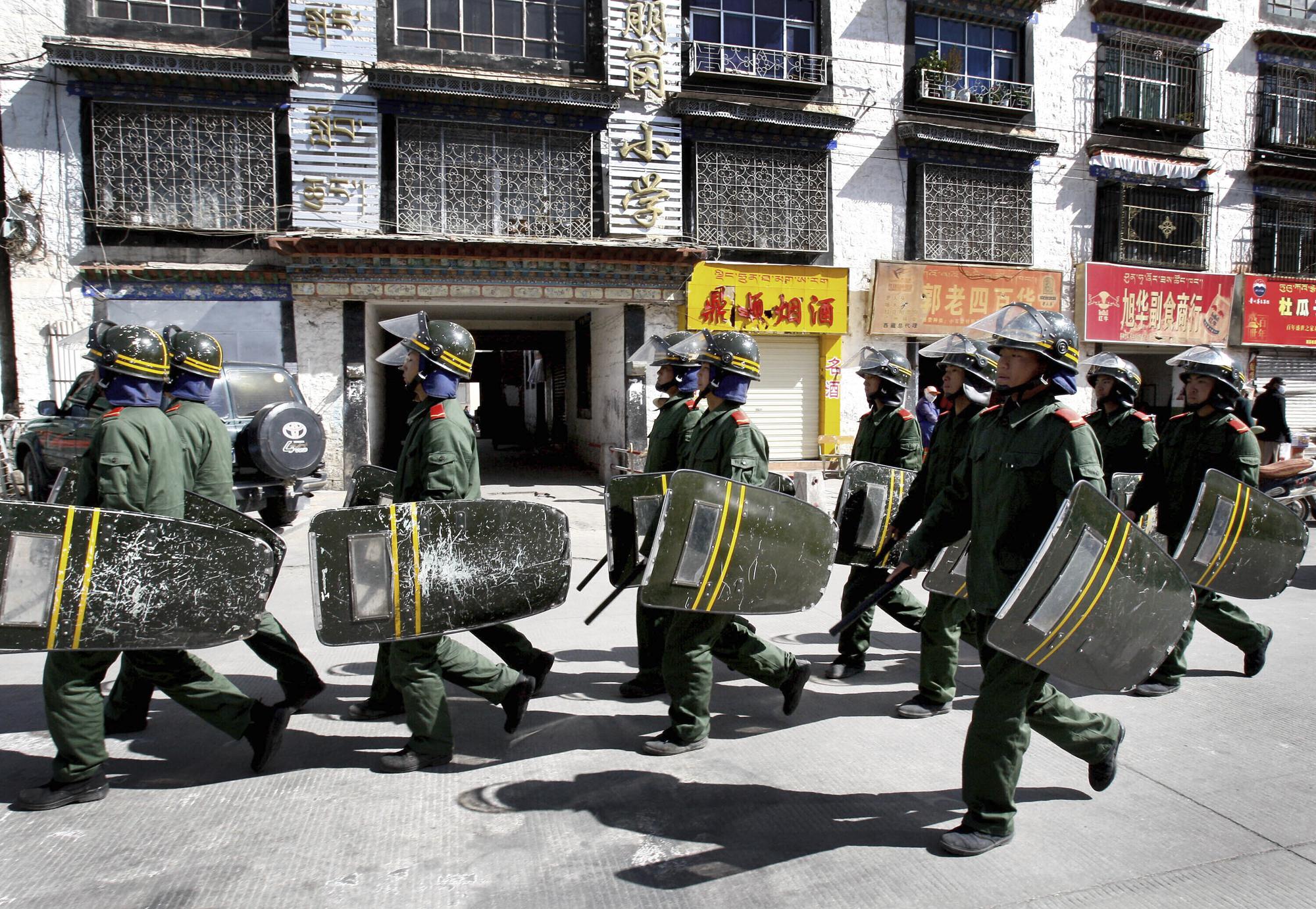 FILE - Chinese paramilitary police patrol on a street in Lhasa, capital of China's Tibet Autonomous Region, on March 27, 2008. Ahead of the Beijing summer Olympics 14 years ago, deadly demonstrations erupted across the Tibetan plateau. But now Tibet has fallen silent, even as the Olympic games come to Beijing again. (AP Photo/Andy Wong, File)