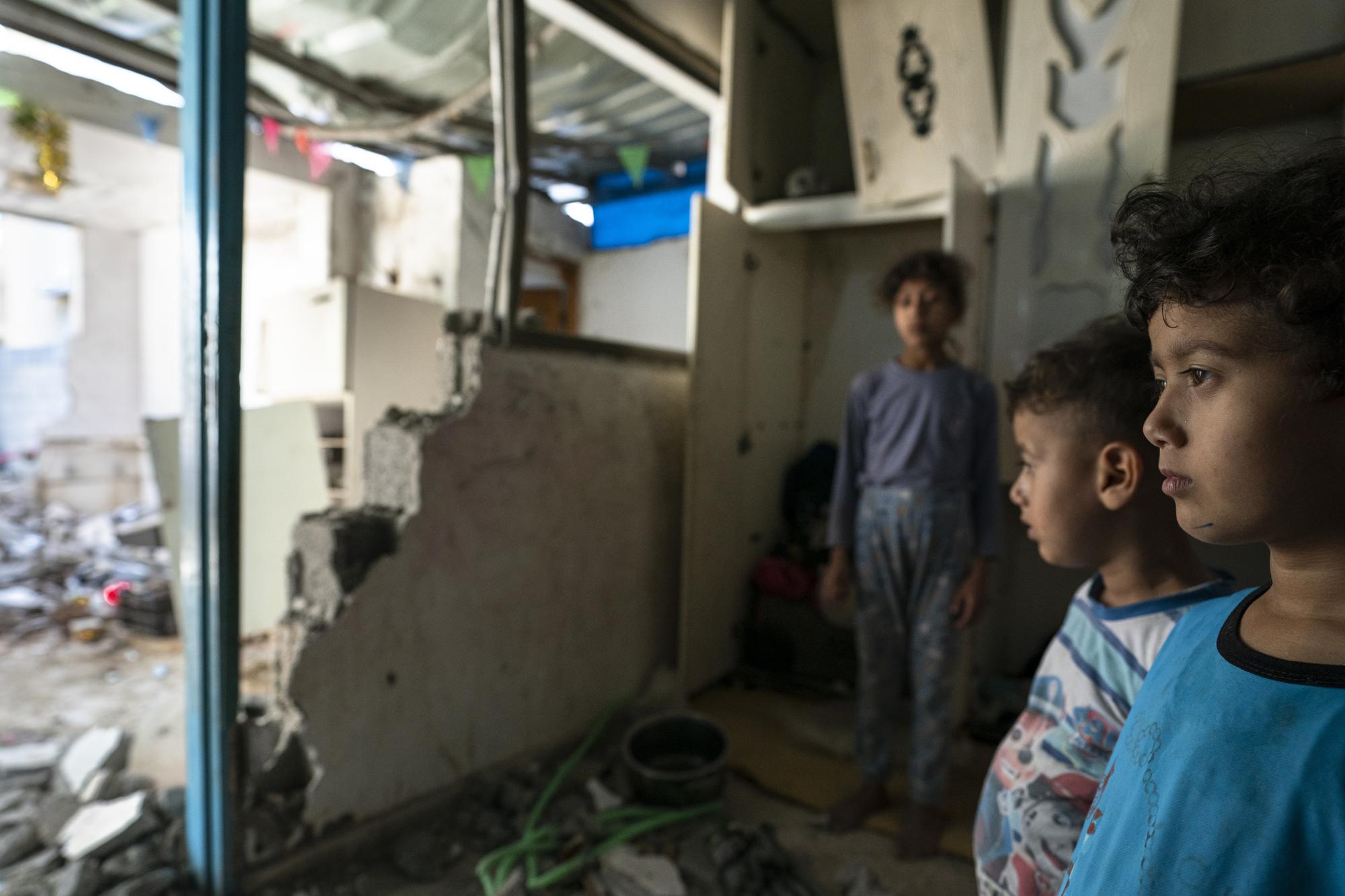 Batul Al-Masri, 5, and her siblings stand for a portrait in their bedroom that was damaged when an airstrike destroyed a nearby building prior to a cease-fire that halted an 11-day war between Gaza's Hamas rulers and Israel, Wednesday, May 26, 2021, in Beit Hanoun, Gaza Strip. (AP Photo/John Minchillo)