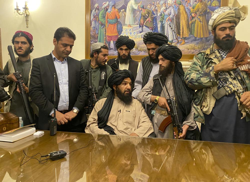 Taliban fighters take control of Afghan presidential palace after the Afghan President Ashraf Ghani fled the country, in Kabul, Afghanistan, Sunday, Aug. 15, 2021. Person second from left is a former bodyguard for Ghani. (AP Photo/Zabi Karimi)