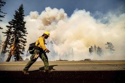 Un bombero camina por la autopista 89 frente al incendio forestal Dixie en el Bosque Navional Lassen, California, el lunes 16 de agosto de 2021. (AP Foto/Noah Berger)