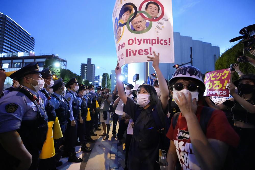 Anti-Olympics protesters, right, stage a rally in front of lines of policemen near National Stadium in Tokyo Friday, July 23, 2021. (Ryosuke Uematsu/Kyodo News via AP)