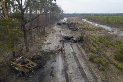 ARCHIVO - Soldados ucranianos están parados junto a vehículos blindados rusos destruidos en las afueras de Kiev el 31 de marzo del 2022. La invasión de Rusia a Ucrania y sus amenazas veladas de usar armas nucleares tienen a legisladores y otros creadores de políticas pensando lo impensable: ¿Cómo debería responder Occidente a la explosión por Rusia de una bomba nuclear en el campo de batalla? (AP Foto/Rodrigo Abd)