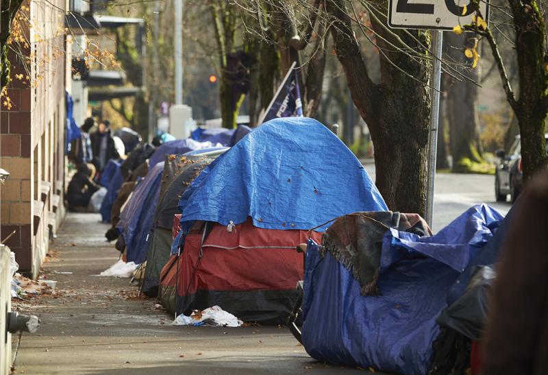 FILE - Tents line the sidewalk on SW Clay St in Portland, Ore., on Dec. 9, 2020. People with disabilities in Portland have filed a class action lawsuit in federal court, Thursday, Sept. 8, 2022, claiming the city has failed to keep sidewalks accessible by allowing homeless tents and encampments to block sidewalks.  (AP Photo/Craig Mitchelldyer, File)