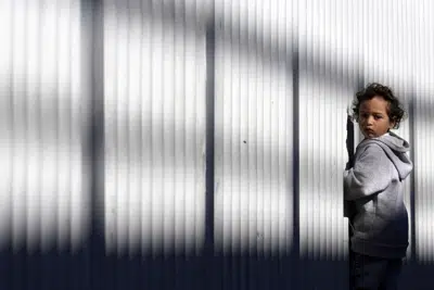 Un niño migrante de pie junto a una cerca en un punto de entrada para solicitantes de asilo en Tijuana, México, el 21 de diciembre de 2022. (AP Foto/Marcio José Sánchez, Archivo)