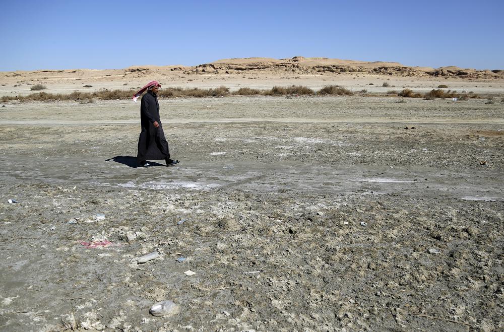 A man walks on saline soil near Razzaza Lake, also known as Lake Milh, Arabic for salt, in the Karbala governorate of Iraq, Feb. 14, 2022. The lake was once a tourist attraction known for its beautiful scenery and an abundance of fish that locals depended on. Dead fish now litter its shores and the once-fertile lands around it have turned into a barren desert. (AP Photo/Hadi Mizban)