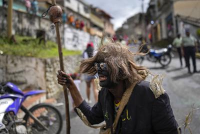 Un hombre vestido de "bolero" durante las celebraciones por el Día de los Inocentes, que recuerda el infanticidio ordenado por el rey Herodes en Belén tras el nacimiento de Jesús según el Evangelio de San Mateo, en Caucagua, Venezuela, el 28 de diciembre de 2021. Los residentes celebran una variación de la fiesta vistiéndose con ropas viejas y pintándose la cara de negro y la lengua de rojo. La tradición, que tiene más de 200 años, es un día de canciones, bailes y bromas. (AP Foto/Matías Delacroix)