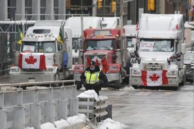 Un policía de pie frente a camiones que bloquean el paso hacia las calles del centro como parte de una protesta contra las medidas impuestas por el COVID-19, el miércoles 9 de febrero de 2022, en Ottawa. (Patrick Doyle/The Canadian Press vía AP)