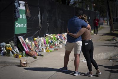 ARCHIVO - Dos personas que conocían a una víctima no identificada de un incidente fatal en el concierto Astroworld se abrazan el domingo 7 de noviembre de 2021 frente a un monumento conmemorativo improvisado en honor a los muertos, en Houston. (AP Foto/Robert Bumsted, archivo)