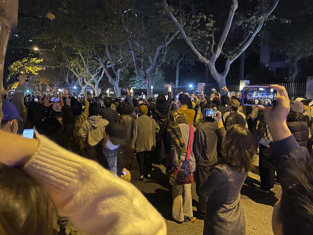 Algunos residentes usan sus celulares para grabar una protesta por un incendio mortal en un edificio residencial en la ciudad china de Urumqi el sábado 26 de noviembre de 2022 en Shanghái, China. (Chinatopix vía AP)