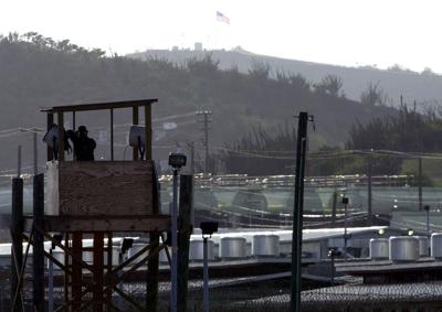 ARCHIVO - En imagen de archivo del 10 de septiembre de 2002, un oficial de la policía militar del Ejército de Estados Unidos observa con binoculares desde una torre de vigilancia en el Campamento Delta en la Base Naval de Estados Unidos en la Bahía de Guantánamo, Cuba. (AP Foto/Lynne Sladky, archivo)