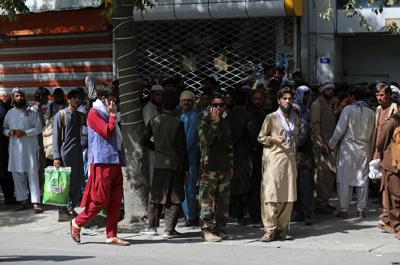 Afganos hacen largas filas el domingo 15 de agosto de 2021 para retirar dinero de un banco, en Kabul, Afganistán. (AP Foto/Rahmat Gul)