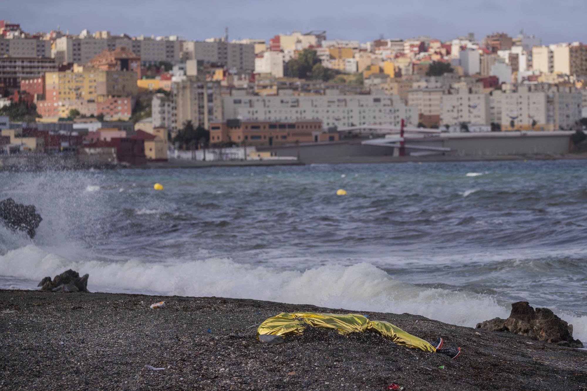 The body of a young man is covered with an emergency blanket after being recovered by Spanish police from waters near the border between Morocco and Spain's north African enclave of Ceuta, Thursday, May 20, 2021. Thousands of migrants jumped or swam around a border fence to reach European soil this week after Morocco loosened its border patrols. (AP Photo/Bernat Armangue)