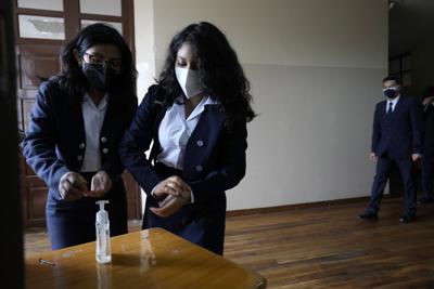 Los estudiantes se desinfectan las manos antes de ingresar a su salón de clases para evitar la propagación del COVID-19 al inicio del año escolar en Quito, Ecuador, el miércoles 1 de septiembre de 2021. (AP Foto/Dolores Ochoa)