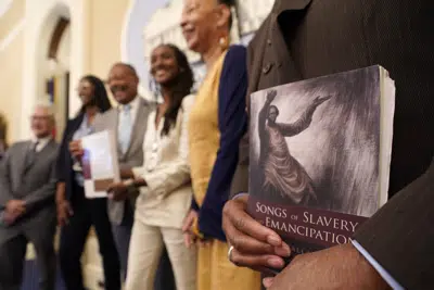 El doctor Amos C. Brown, Jr., vicepresidente de la comisión de California para reparaciones a afroestadounidenses, a la derecha, sujeta un libro en el momento en que él y otros miembros de la comisión posan para fotos en el Capitolio en Sacramento, California, el 16 de junio de 2022. (Foto AP/Rich Pedroncelli)