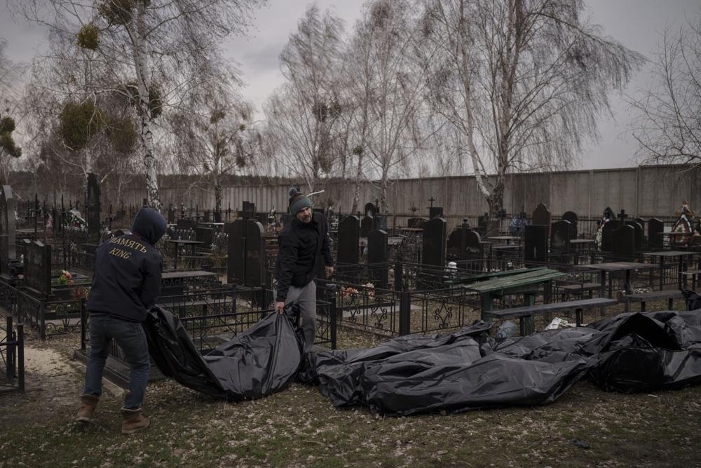 Workers carry the body of people found dead to a cemetery in Bucha, outskirts of Kyiv, Ukraine, Tuesday, April 5, 2022. Ukraine’s president told the U.N. Security Council on Tuesday that the Russian military must be brought to justice immediately for war crimes, accusing invading troops of the worst atrocities since World War II. He stressed that Bucha was only one place and there are more with similar horrors. (AP Photo/Felipe Dana)