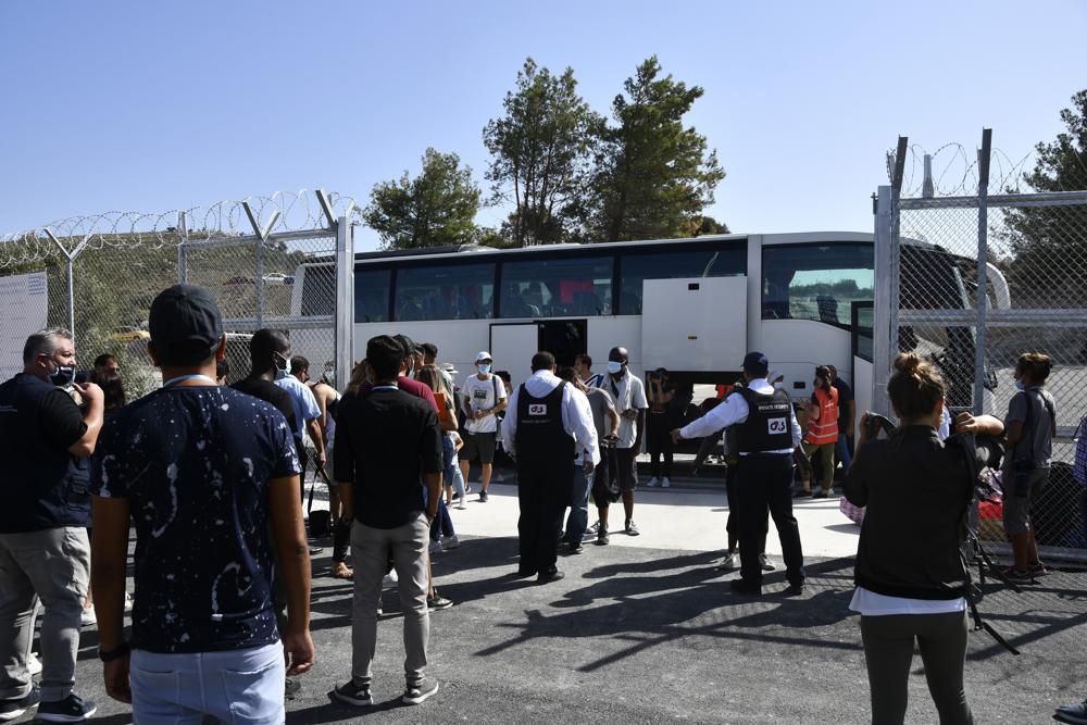 Security personnel check migrants upon their arrival at the new closed monitored facility in Zervou village, on the eastern Aegean island of Samos, Greece, Monday, Sept. 20, 2021. The transfer of the migrants to the new, €43 million ($50 million) facility began Monday and be completed by Wednesday. (AP Photo/Michael Svarnias)