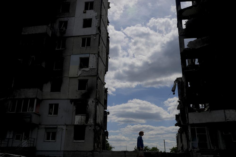 A woman walks in front of buildings destroyed during attacks in Borodyanka, on the outskirts of Kyiv, Ukraine, Saturday, June 4, 2022. (AP Photo/Natacha Pisarenko)