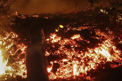 Una persona permanece de pie frente a la lava de la erupción del Monte Nyiragongo, en Buhene, a las afueras de Goma, en las primeras horas del domingo 23 de mayo de 2021, en la República Democrática del Congo. (AP Foto/Justin Kabumba)