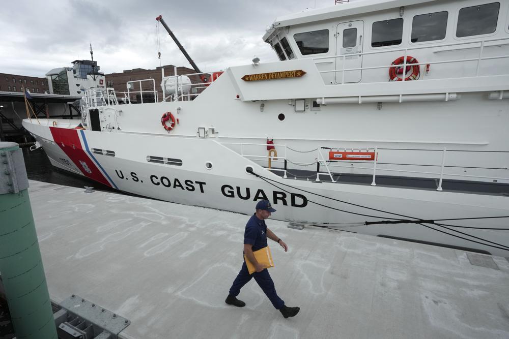 ARCHIVO - El patrullero de la Guardia Costera de EE. UU. Warren Deyampert atraca mientras un miembro de la Guardia Costera pasa caminando, el martes 20 de junio de 2023, en la Base de la Guardia Costera de Boston, en Boston.  Los rescatistas corren contra el tiempo para encontrar el sumergible desaparecido que transportaba a cinco personas, que se reportaron retrasadas el domingo por la noche, 18 de junio de 2023. (Foto AP/Steven Senne, archivo)