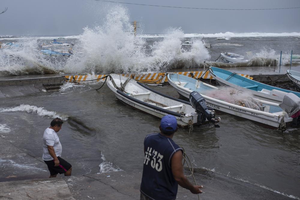 Dos pescadores retiran sus botes del muelle el viernes 20 de agosto de 2021 en el estado mexicano de Veracruz, en preparación para la llegada del huracán Grace. (AP Foto/Félix Márquez)