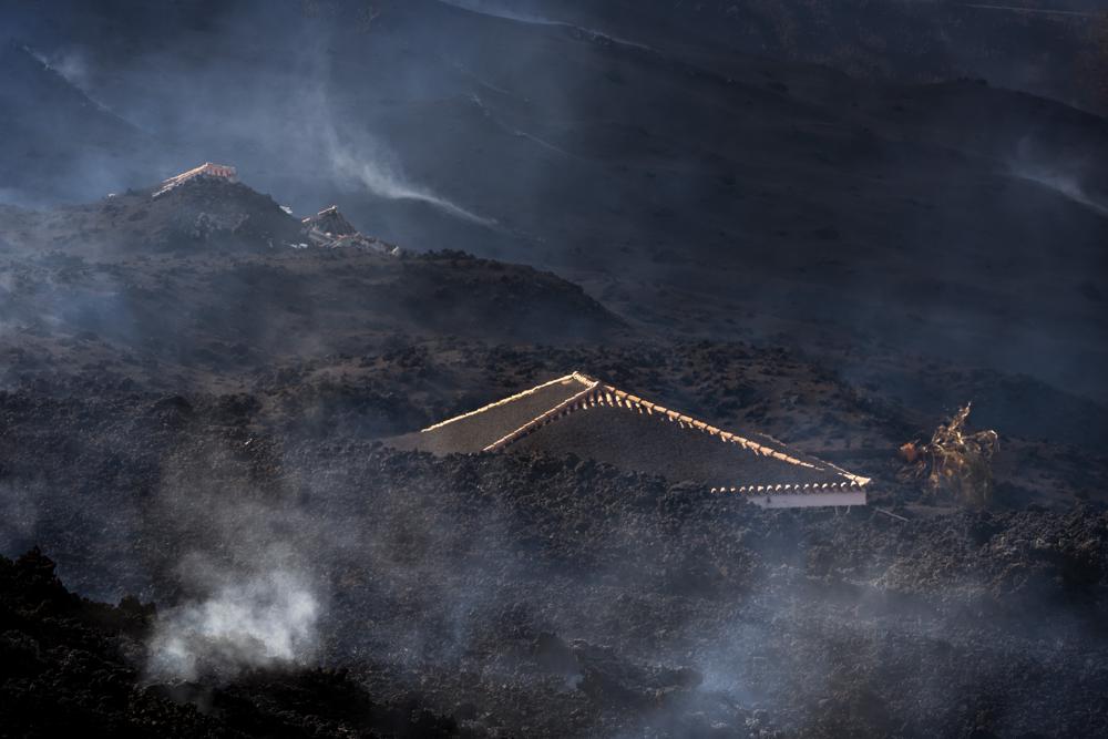 Una casa está cubierta de escombros después de la erupción de un volcán cerca de El Paso en la isla de La Palma en las Canarias, España, el martes 21 de septiembre de 2021. Un volcán inactivo en una pequeña isla española en el Océano Atlántico entró en erupción el domingo , obligando a la evacuación de miles de personas.  Enormes columnas de humo blanco y negro se dispararon desde una cresta volcánica donde los científicos habían estado monitoreando la acumulación de lava fundida debajo de la superficie.  (Foto AP / Emilio Morenatti)