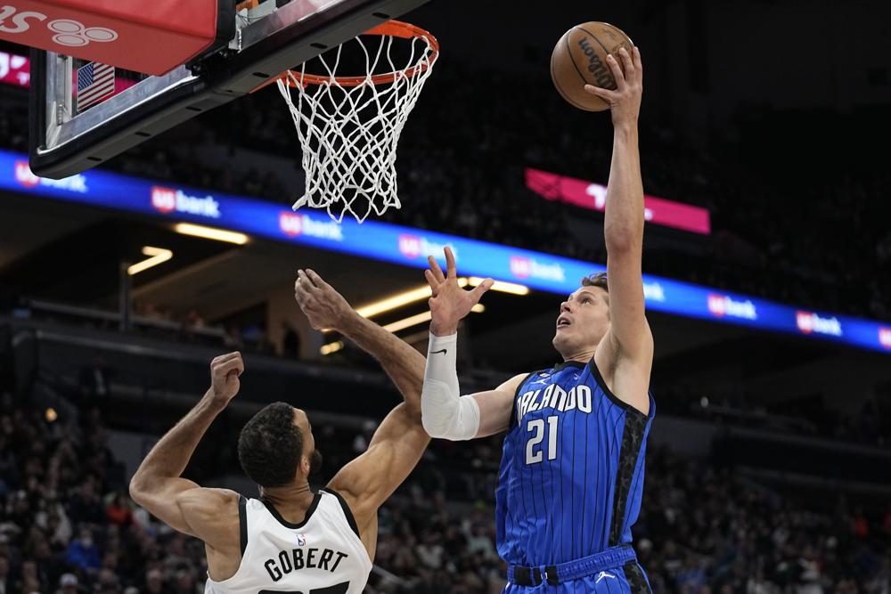 Orlando Magic center Moritz Wagner (21) shoots while defended by Minnesota Timberwolves center Rudy Gobert during the second half of an NBA basketball game, Friday, Feb. 3, 2023, in Minneapolis. (AP Photo/Abbie Parr)