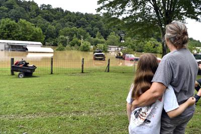 Bonnie Combs, right, hugs her 10-year-old granddaughter Adelynn Bowling watches as her property becomes covered by the North Fork of the Kentucky River in Jackson, Ky., Thursday, July 28, 2022. Flash flooding and mudslides were reported across the mountainous region of eastern Kentucky, where thunderstorms have dumped several inches of rain over the past few days. (AP Photo/Timothy D. Easley)