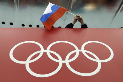 En esta imagen de archivo, una bandera rusa ondea sobre los anillos olímpicos en el centro de patinaje Adler Arena, durante los Juegos Olímpicos de Invierno de Sochi, Rusia, el 18 de febrero de 2014. (AP Foto/David J. Phillip, archivo)
