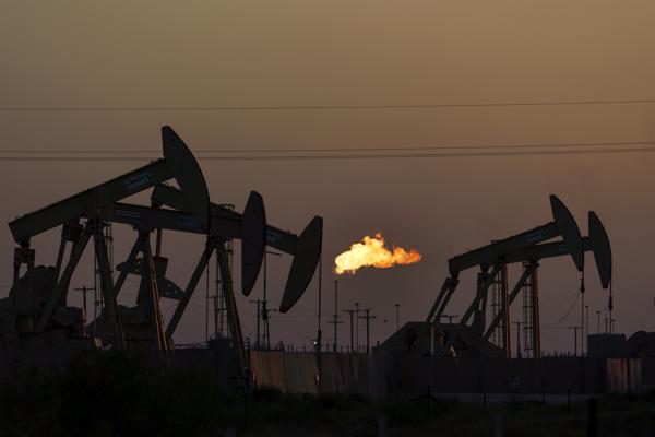 A flare burns off methane and other hydrocarbons as oil pumpjacks operate in the Permian Basin in Midland, Texas, Tuesday, Oct. 12, 2021. Massive amounts of methane are venting into the atmosphere from oil and gas operations across the Permian Basin, new aerial surveys show. The emission endanger U.S. targets for curbing climate change.  (AP Photo/David Goldman)