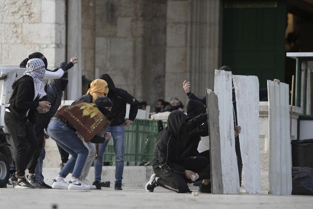 Manifestantes palestinos usan escudos improvisados ​​durante los enfrentamientos con la policía israelí en el recinto de la Mezquita de Al Aqsa en la Ciudad Vieja de Jerusalén, el viernes 22 de abril de 2022. La policía israelí y los jóvenes palestinos se enfrentaron nuevamente en el principal lugar sagrado de Jerusalén sagrado para judíos y musulmanes el viernes a pesar de un interrupción temporal de las visitas judías al sitio, que los palestinos consideran una provocación.  (Foto AP/Mahmoud Illean)