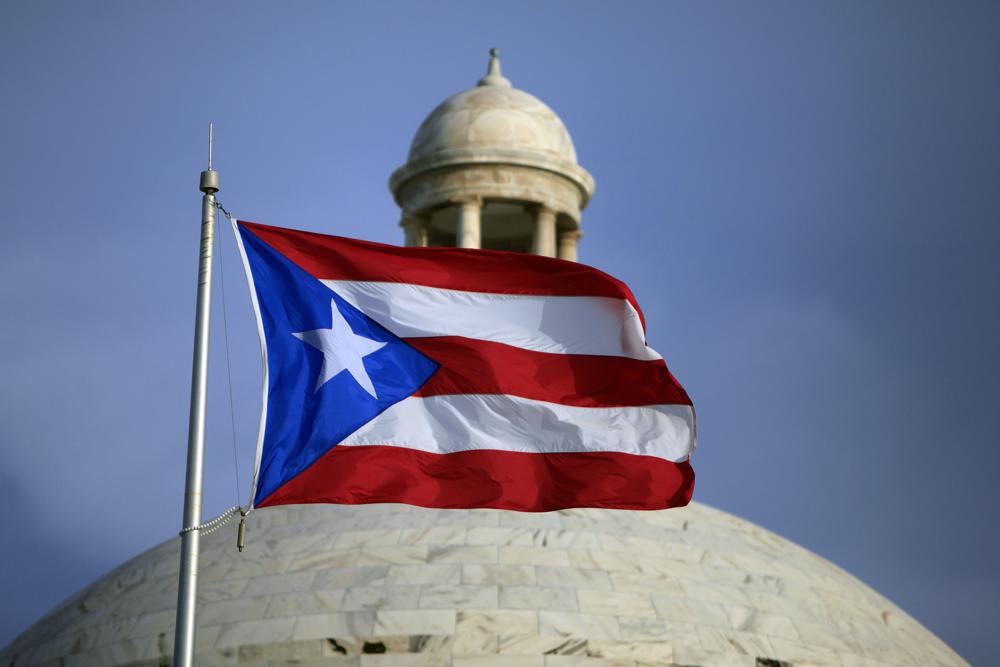 FILE -  The Puerto Rican flag flies in front of Puerto Rico's Capitol as in San Juan, Puerto Rico, July 29, 2015. A group of Democratic congress members, including the House majority leader, on Thursday, May 19, 2022, proposed a binding plebiscite to decide whether Puerto Rico should become a state or gain some sort of independence. (AP Photo/Ricardo Arduengo, File)