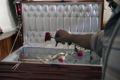 Un amigo coloca una rosa en el ataúd de cara abierta que contiene los restos del periodista asesinado Armando Linares en Zitacuaro, en el estado de Michoacán, México, el miércoles 16 de marzo de 2022. Linares fue asesinado a tiros en una casa en la ciudad de Zitacuaro el martes, el octavo periodista mexicano asesinado en lo que va del año. (AP Foto/Marco Ugarte)