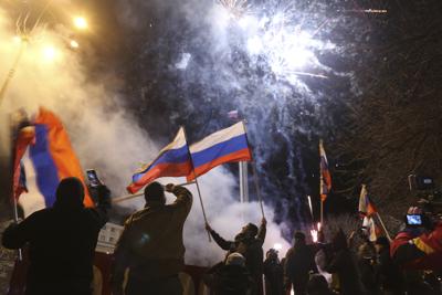 Personas celebran el reconocimiento de independencia ondeando banderas de Rusia en el centro de Donetsk, territorio controlado por rebeldes prorrusos, el lunes 21 de febrero de 2022, en el este de Ucrania. (AP Foto/Alexei Alexandrov)