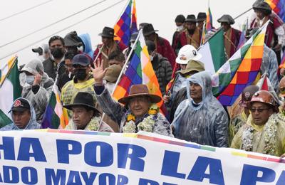 El presidente de Bolivia, Luis Arce, en el centro, saluda mientras camina con su vicepresidente David Choquehuanca, segundo a la izquierda, y con el expresidente Evo Morales, segundo a la derecha, durante una marcha en La Paz, Bolivia, el lunes 29 de noviembre de 2021. Choquehuanca ha quedado en medio de las críticas por su supuesta negativa a vacunarse contra el COVID-19 y puso en apuros al gobierno, que acaba de aprobar un decreto que obliga a los bolivianos a portar un pase sanitario. (AP Foto/Juan Karita)