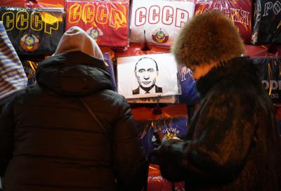 Personas frente a un local que vende camisetas de la URSS y del presidente ruso Vladimir Putin en una calle en San Petersburgo, Rusia, el lunes 13 de diciembre de 2021. (AP Foto/Dmitri Lovetsky).