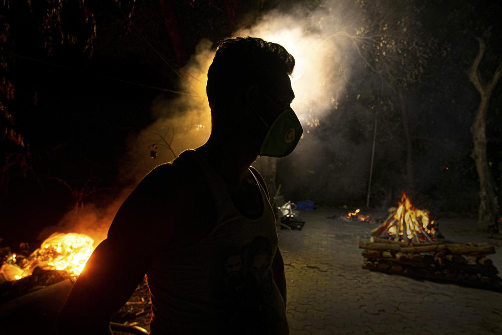 FILE - In this Sept. 14, 2020, file photo, Ramananda Sarkar, 43, who has cremated more than 450 COVID-19 victims stands by burning funeral pyres of COVID-19 victims in Gauhati, India. Indias excess deaths during the pandemic could be a staggering 10 times the official COVID-19 toll, likely making it modern Indias worst human tragedy, according to the most comprehensive research yet on the ravages of the virus in the south Asian country. (AP Photo/Anupam Nath, File)