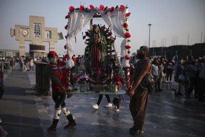 Dos feligreses cargan una imagen de la Virgen de Guadalupe durante un peregrinaje a la basílica en su honor, el viernes 10 de diciembre de 2021, en la Ciudad de México. (AP Foto/Emilio Espejel)