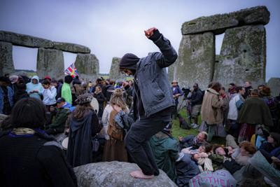 Un grupo de personas permanece en el interior del círculo de piedras durante el solsticio de verano en Stonehenge, donde algunos saltaron la valla para ingresar al área y ver el amanecer del día más largo del año en el Reino Unido, en Amesbury, Inglaterra, el lunes 21 de junio de 2021. (Ben Birchall/PA vía AP)