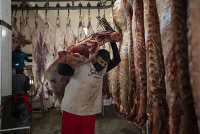 Un trabajador transporta una media res en Buenos Aires, Argentina, el miércoles 19 de mayo de 2021. Los productores agropecuarios argentinos iniciaron el jueves un paro de ocho días contra el cierre de las exportaciones de carne vacuna dispuesto por el presidente Alberto Fernández.  (AP Foto/Víctor R. Caivano)