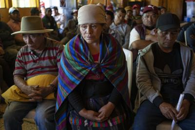 Magdalena Tepaz, centro, y Manuel de Jesús Tulul, derecha, padres de Wilmer Tulul, esperan el inicio de una reunión comunitaria en Tzucubal, Guatemala, el miércoles 29 de junio de 2022. Wilmer y su primo Pascual, ambos de 13 años, figuraban entre los decenas muertos encontrados dentro de un camión con remolque cerca de los patios de chatarra de automóviles en las afueras de San Antonio, Texas, el lunes, en lo que se cree que es el episodio de contrabando humano más mortífero en Estados Unidos. (Foto AP/Moisés Castillo)