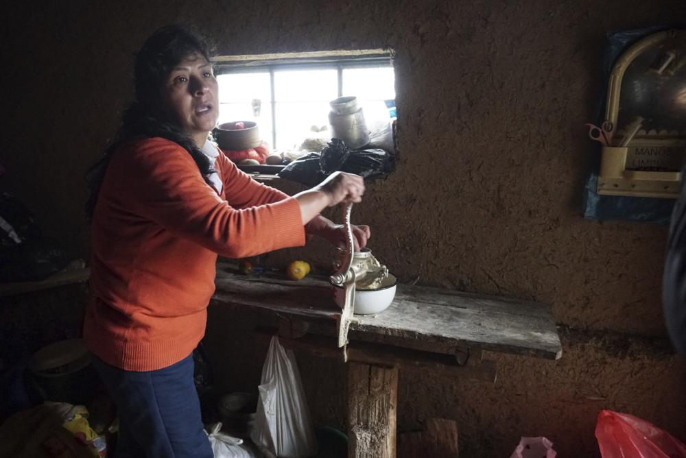 La futura primera dama de Perú, Lilia Paredes, de 48 años, muele pedazos de queso para preparar el desayuno en la cocina de su casa de adobe el jueves 22 de julio de 2021, en la localidad rural de Chugur, Perú. (AP Foto/Franklin Briceño)