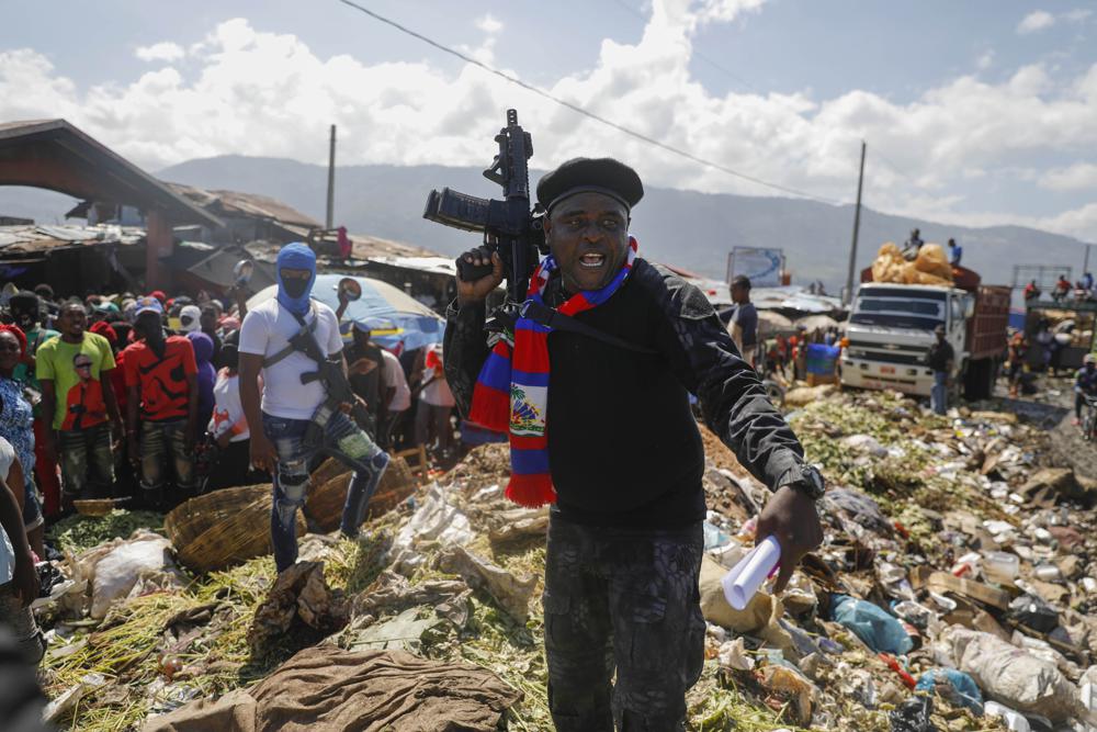 FILE - Barbecue, the leader of the G9 and Family gang, stands next to garbage to call attention to the conditions people live in as he leads a march against kidnapping through La Saline neighborhood in Port-au-Prince, Haiti, Friday, Oct. 22, 2021. The group said they were also protesting poverty and for justice in the slaying of President Jovenel Moise. (AP Photo/Odelyn Joseph, File)