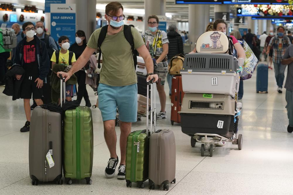 A family and their pets walk through Miami International Airport, Monday, Dec. 20, 2021, in Miami. Public health officials are urging caution as the new omicron variant might become the dominant strain in the U.S. during the holiday break. (AP Photo/Marta Lavandier)