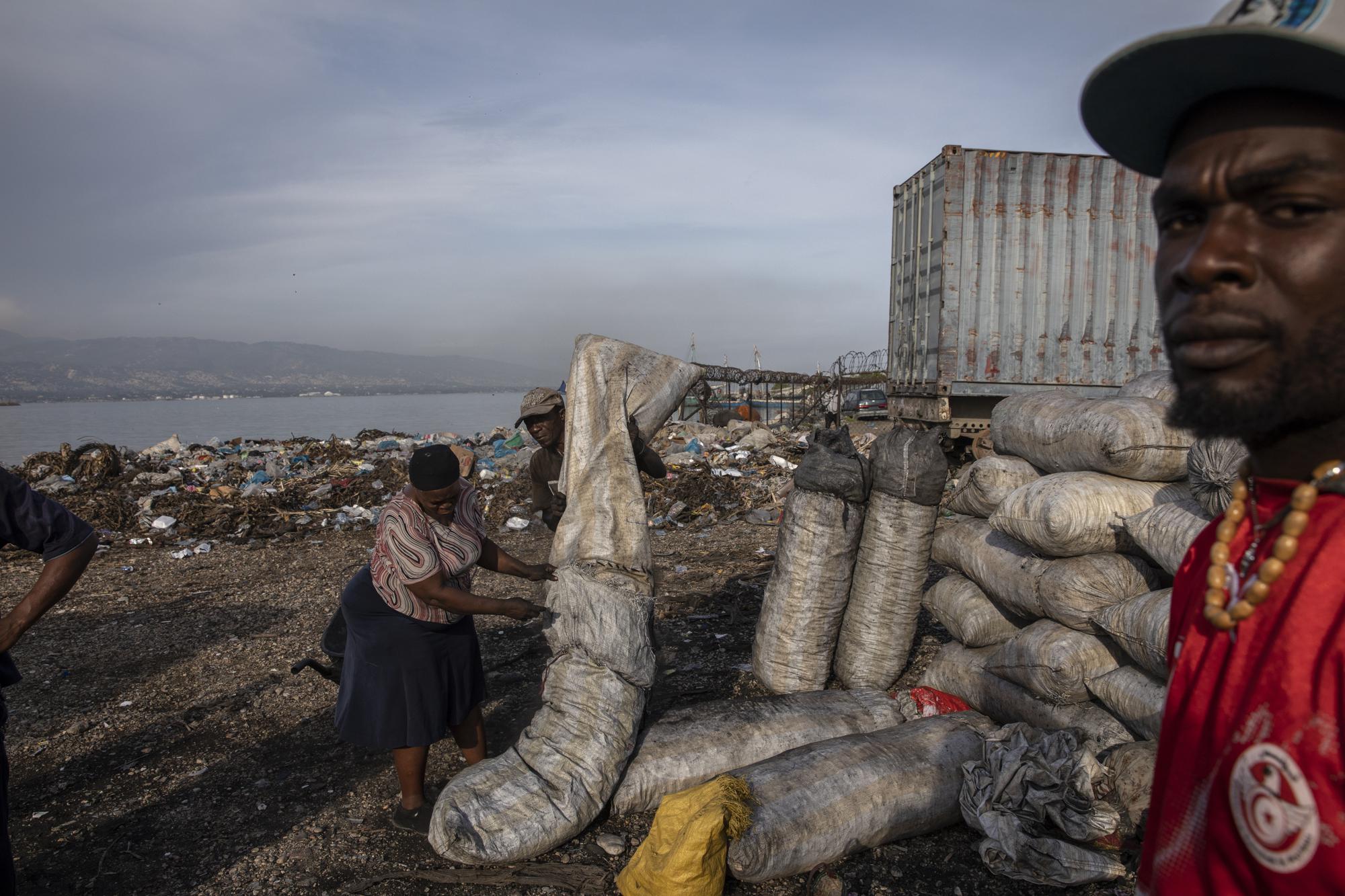 A woman packs charcoal to sell at a market in downtown Port-au-Prince, Haiti, Wednesday, Sept. 22, 2021. Deportees join thousands of fellow Haitians who have been displaced from their homes, pushed out by violence to take up residence in crowded schools, churches, sports centers and makeshift camps among ruins. (AP Photo/Rodrigo Abd)